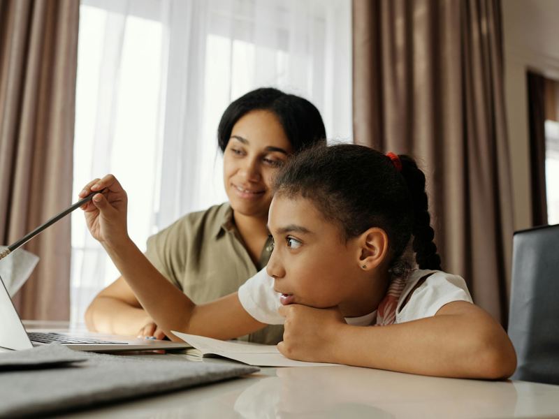 mother and daughter engaged in online learning at home, using a laptop image