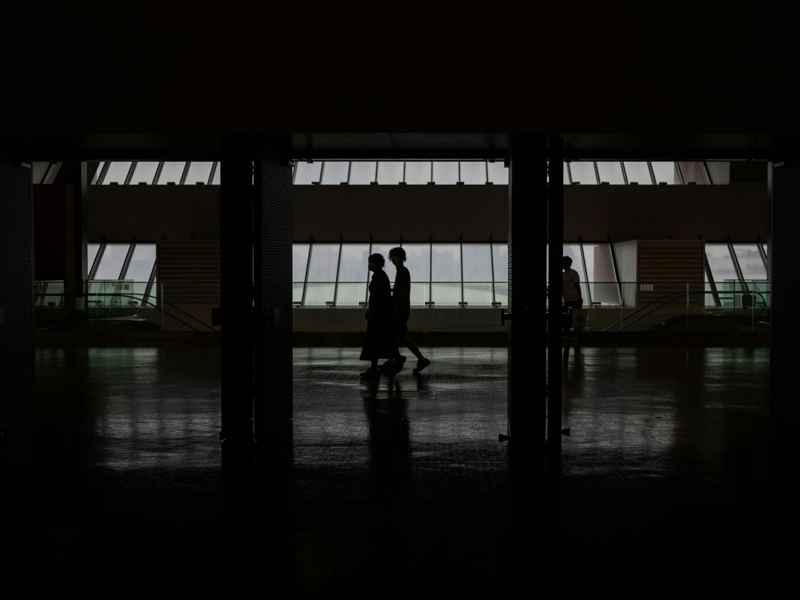 silhouette of people walking through a modern hallway with large windo image